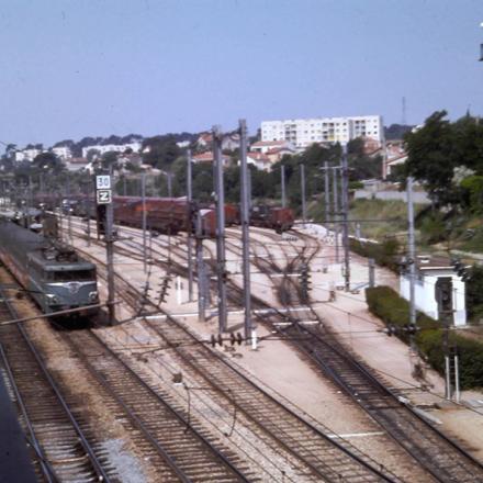 Le convoi stationne voie 3 tandis que sur voie 1 passe sans arrêt un rapide de la côte d’Azur qui semble être un train d’agence avec voitures Wasteel.
